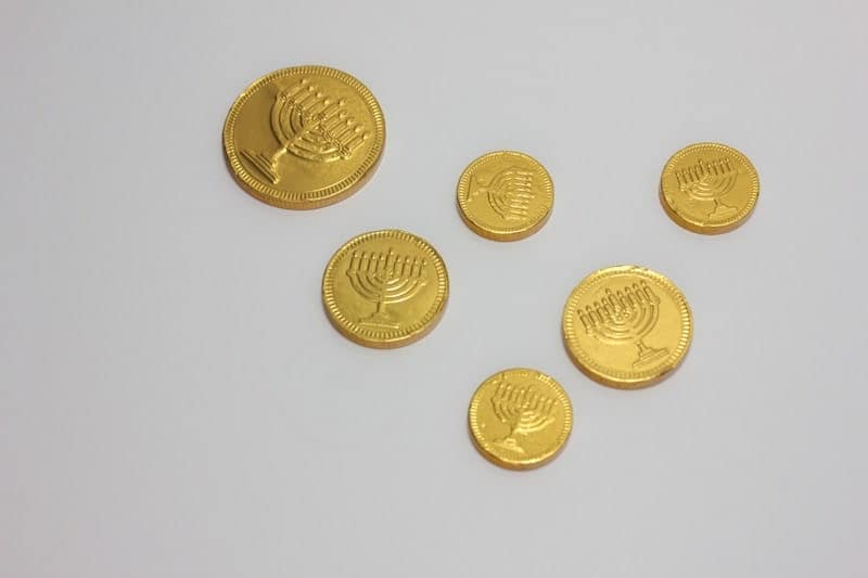 Gold chocolate Hanukkah coins (gelt) embossed with menorahs on white background.