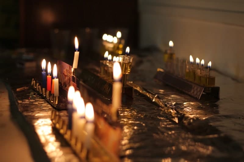 Hanukkah menorahs with colorful candles and oil lamps lit for the holiday celebration.