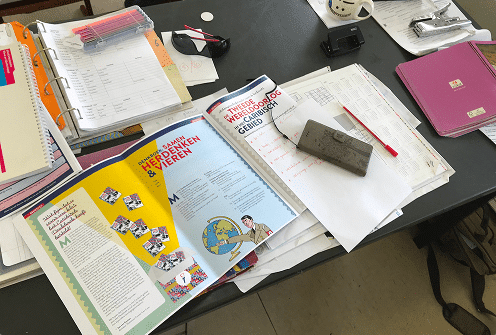 School desk with colorful books, documents, and study materials displayed, related to Jewish education at Curaçao museum.