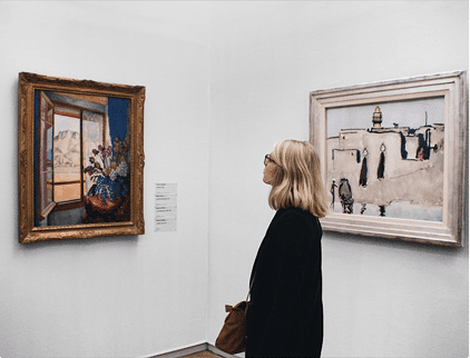 Woman viewing paintings at the Jewish Museum Curaçao, exploring Jewish culture through art.