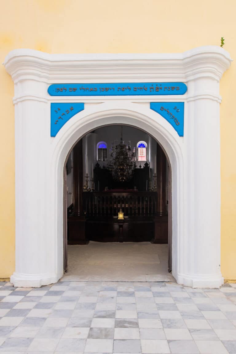 Ornate entrance to the historic synagogue in Curaçao, featuring Hebrew inscriptions and leading to the main sanctuary of the Jewish Museum.