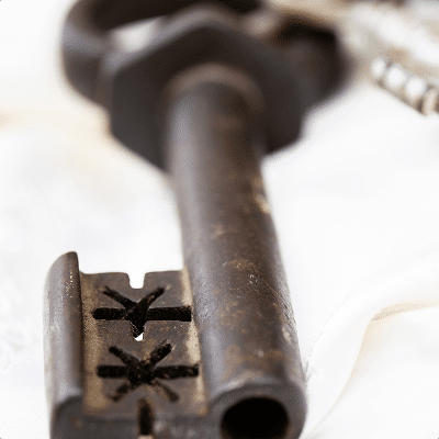 Old iron key with star-shaped notches on a white background.