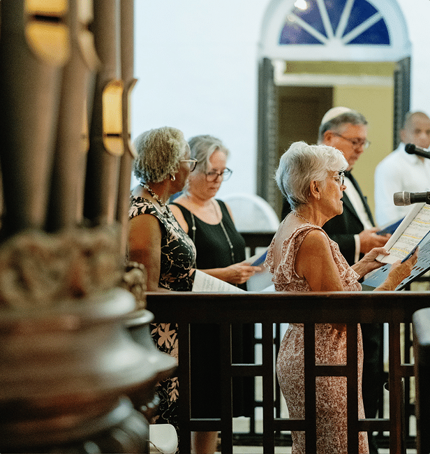 Visitors reading from printed materials during a tour inside the Mikvé Israel-Emanuel Synagogue.